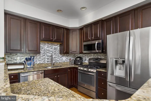 a kitchen with stainless steel appliances granite countertop wooden cabinets a stove a sink and a microwave
