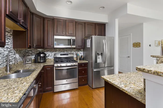 a kitchen with kitchen island granite countertop a sink stove and refrigerator