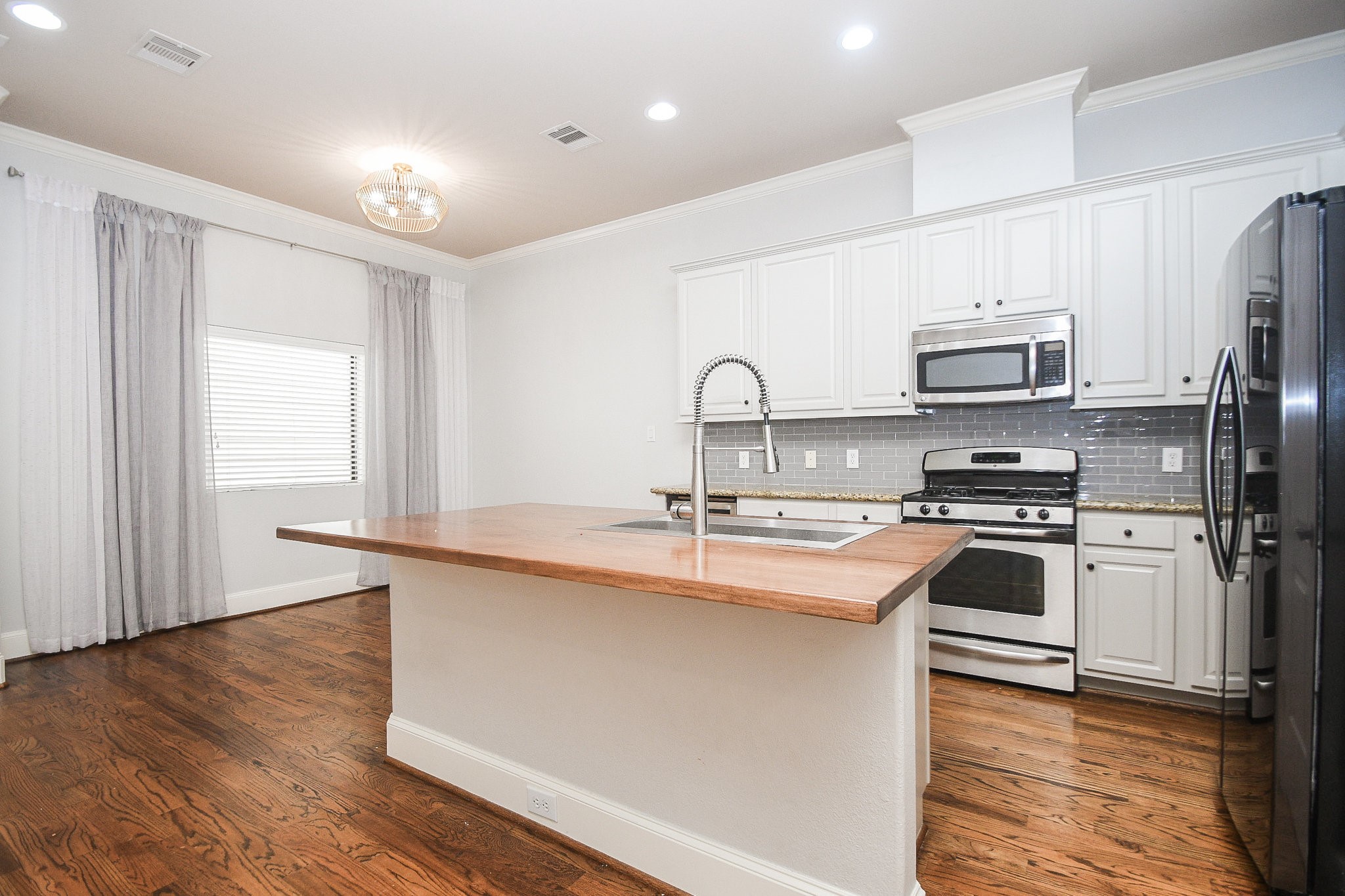 1222 West 17th Street, Unit D Houston, TX 77008 - Photo 7 of 35 a kitchen with stainless steel appliances granite countertop a stove a sink dishwasher a refrigerator and a microwave oven with wooden floor
