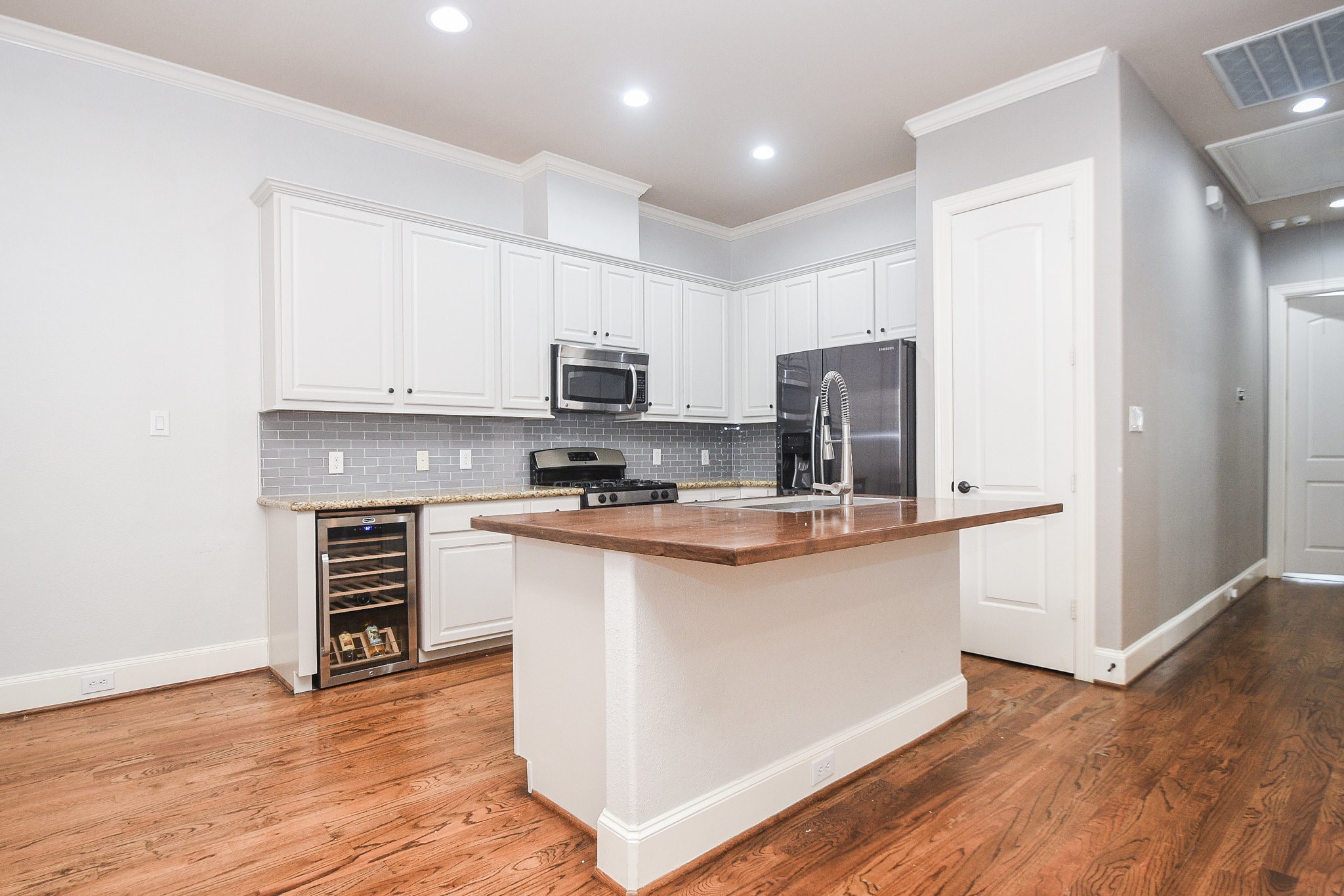 1222 West 17th Street, Unit D Houston, TX 77008 - Photo 8 of 35 a kitchen with stainless steel appliances a microwave a stove a sink dishwasher a refrigerator and white cabinets with wooden floor