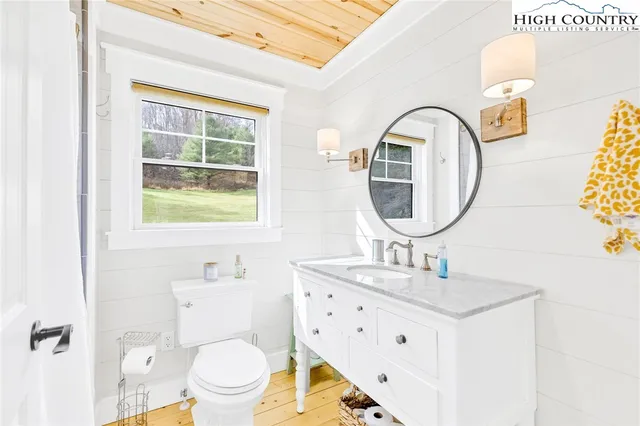 a bathroom with a sink a mirror a toilet and a window