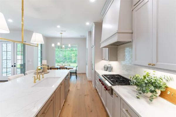 a large kitchen with kitchen island a stove a chimney a sink and living room view