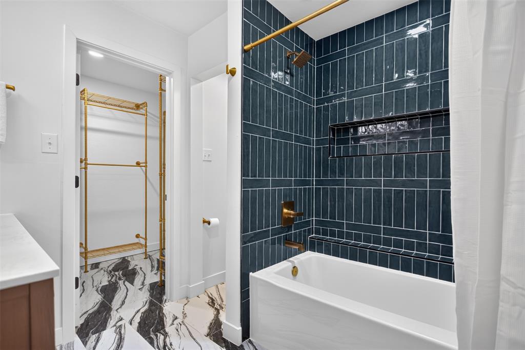 1101 Signal Ridge Place Rockwall, TX 75032 - Photo 14 of 20 Bathroom featuring a deep soaking tub with a dark blue subway tile surround and a built-in shower niche attached custom closet