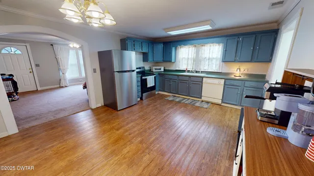 a kitchen with stainless steel appliances granite countertop a refrigerator a sink dishwasher a stove and white countertops with wooden floor