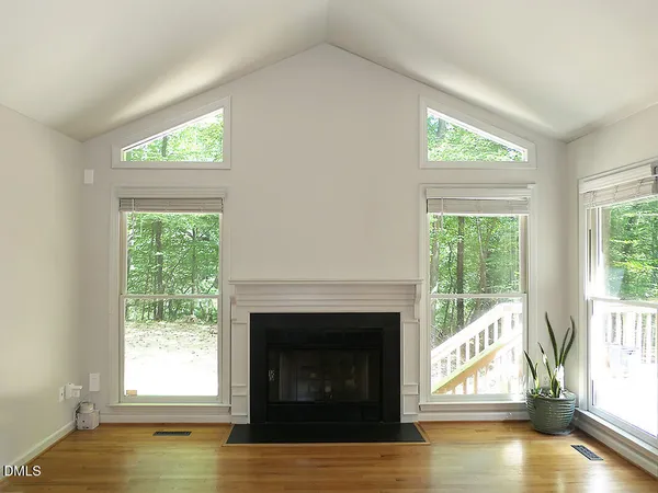 a view of empty room with wooden floor and fireplace