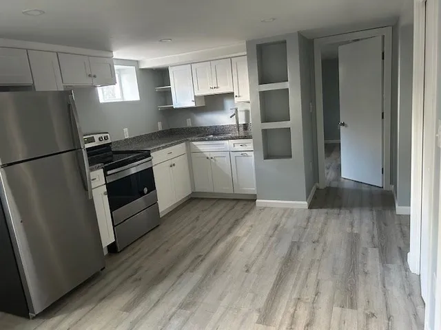 a kitchen with a refrigerator a stove top oven and wooden floor
