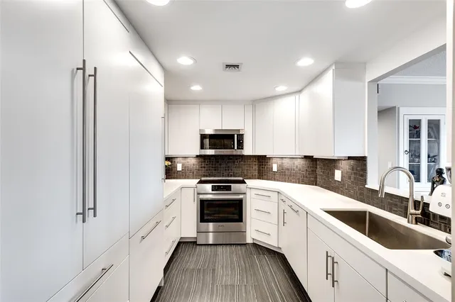 a kitchen with granite countertop white cabinets and white stainless steel appliances