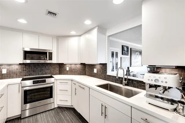 a kitchen with white cabinets sink and stainless steel appliances