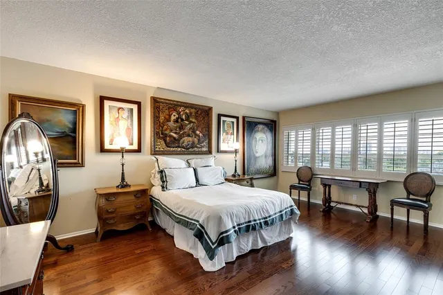 a bedroom with a bed a table and chair with wooden floor