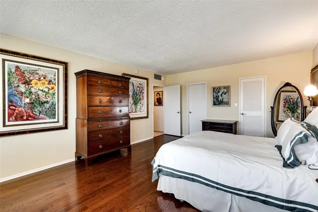 a bedroom with a bed and a dresser with wooden floor