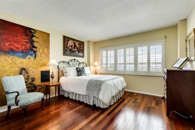 a spacious bedroom with a bed and wooden floor