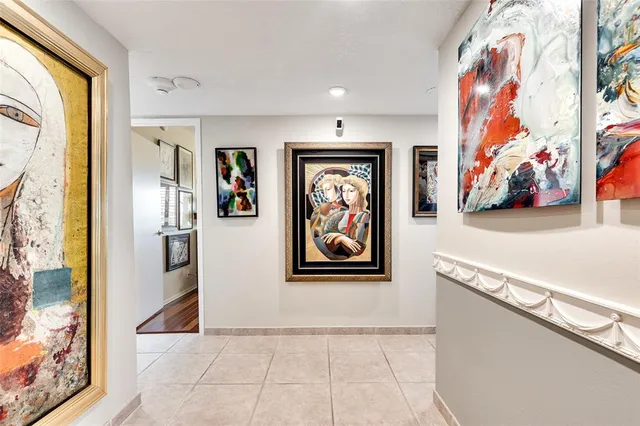 a view of a hallway with paintings on the wall and a large window