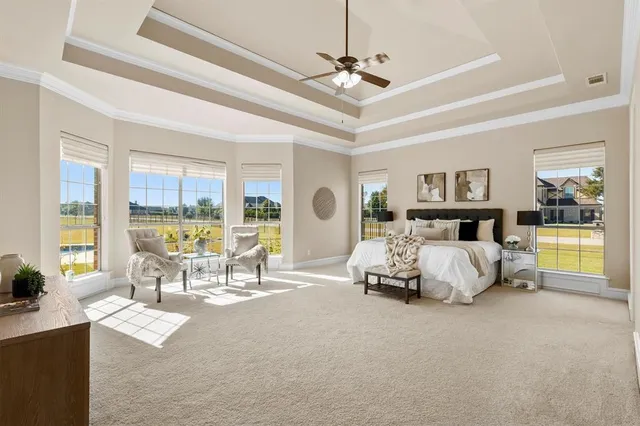 a spacious bedroom with a large bed and a chandelier fan