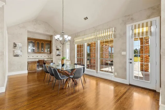 a dining room with wooden floor a chandelier a wooden table and chairs