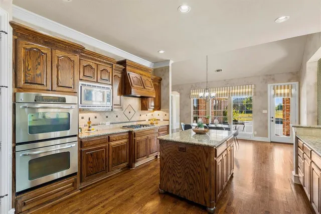 a large kitchen with stainless steel appliances granite countertop a lot of counter space and wooden floors