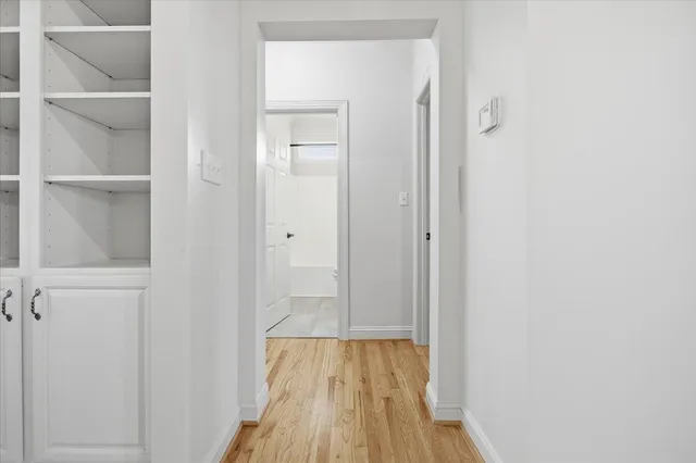 a view of an empty room with chandelier fan and wooden floor