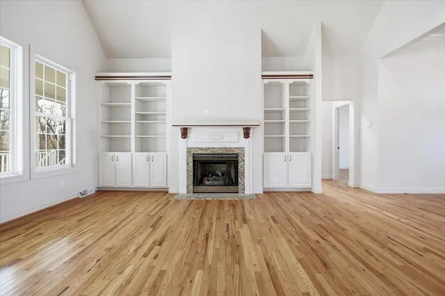 a view of an empty room with a window and wooden floor