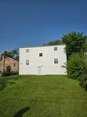 a backyard of a house with plants and large tree