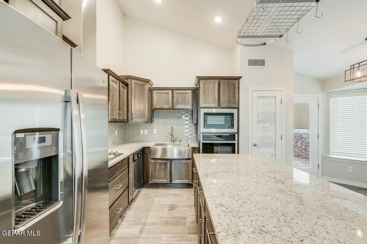 6058 Fall Ridge Street Sunland Park, NM 88008 - Photo 8 of 26 a large kitchen with stainless steel appliances kitchen island granite countertop a refrigerator and stove top oven