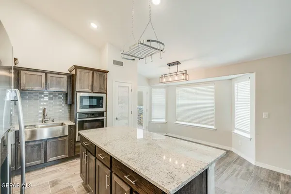 a kitchen with stainless steel appliances granite countertop a sink a stove and refrigerator