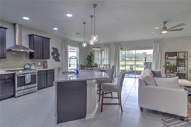 a kitchen with stainless steel appliances granite countertop a stove top oven a sink dishwasher a dining table and chairs with wooden floor