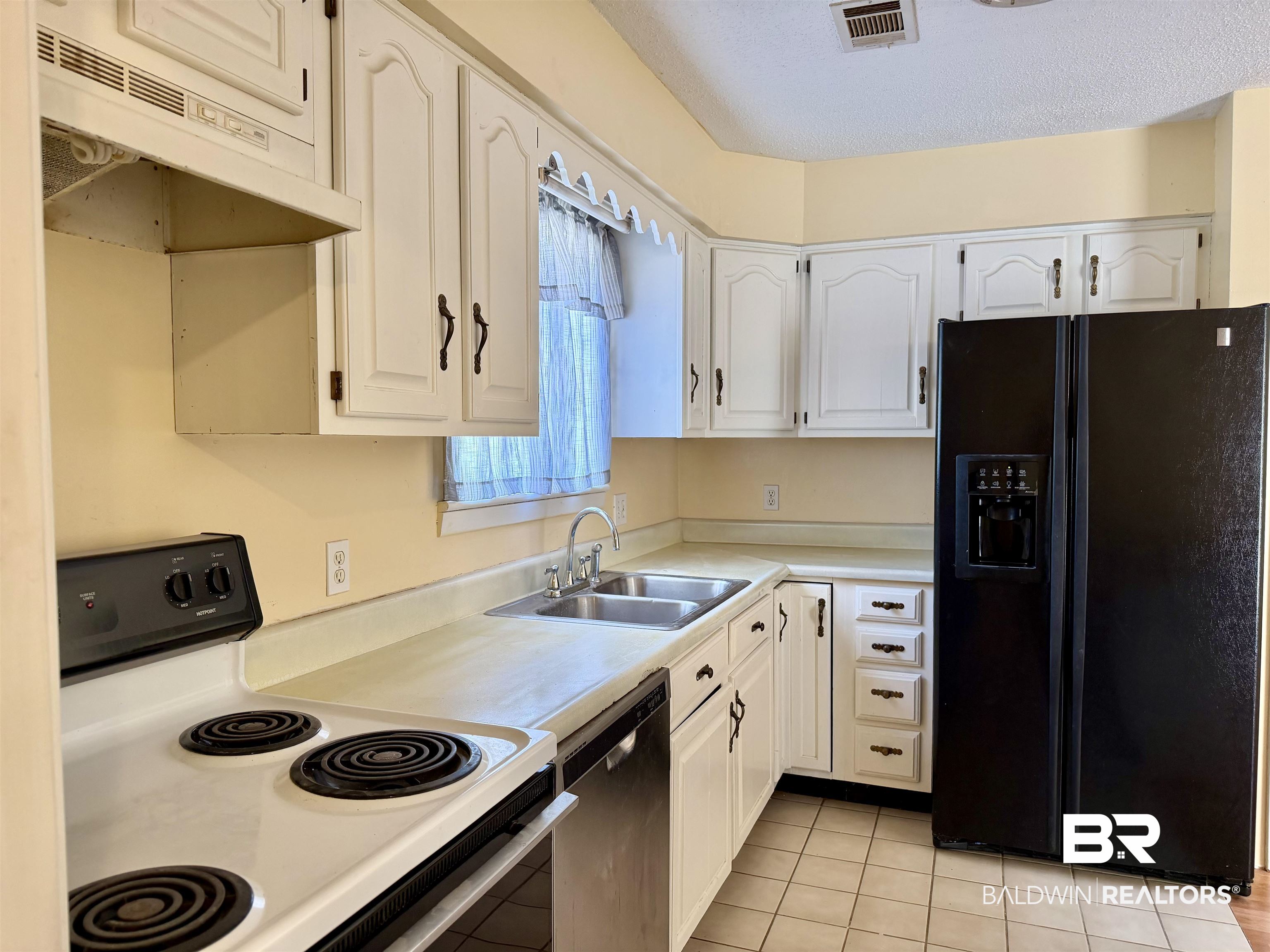 294 Wolf Log Road Flomaton, AL 36441 - Photo 6 of 14 Kitchen featuring black refrigerator with ice dispenser, white electric range oven, white cabinets, light countertops, and a textured ceiling