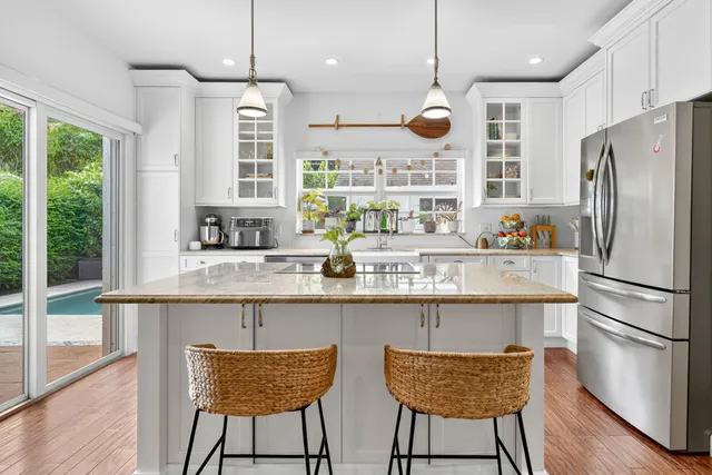 a kitchen with stainless steel appliances granite countertop a stove top oven a refrigerator a sink and chairs with wooden floor