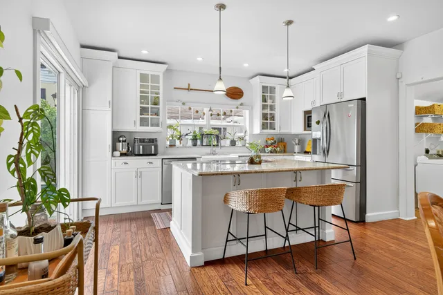 a kitchen with stainless steel appliances granite countertop a refrigerator a stove a sink dishwasher and white cabinets with wooden floor