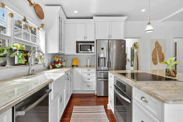 a kitchen with granite countertop a sink stainless steel appliances and white cabinets