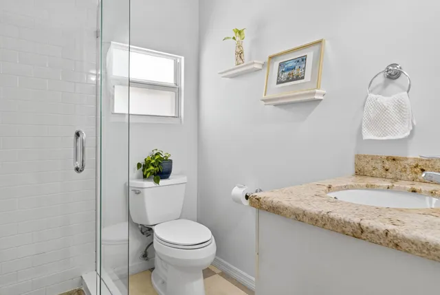 a bathroom with a granite countertop sink a toilet and a mirror