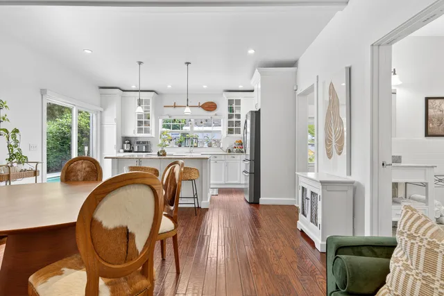 a kitchen with stainless steel appliances granite countertop a stove a refrigerator a sink dishwasher a dining table and chairs with wooden floor