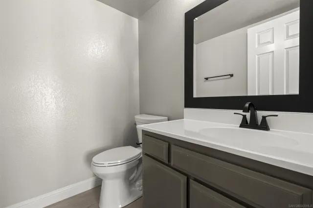 a bathroom with a granite countertop sink a toilet and a mirror