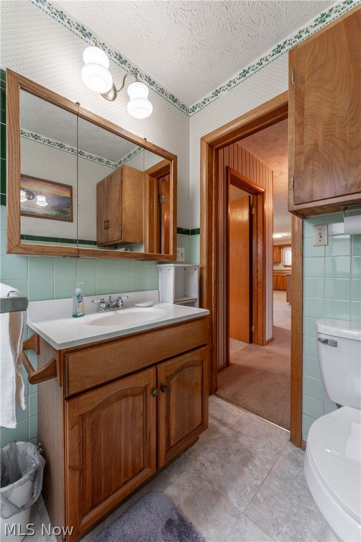 4833 Angling Road Wooster, OH 44691 - Photo 26 of 49 Bathroom featuring toilet, a textured ceiling, vanity with extensive cabinet space, tile walls, and tile flooring