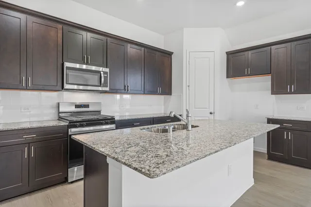 a kitchen with kitchen island granite countertop a sink stove and microwave