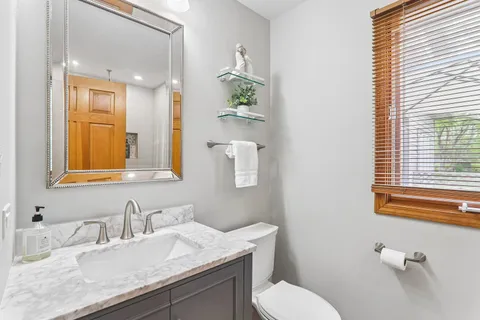 a bathroom with a granite countertop sink mirror and a toilet