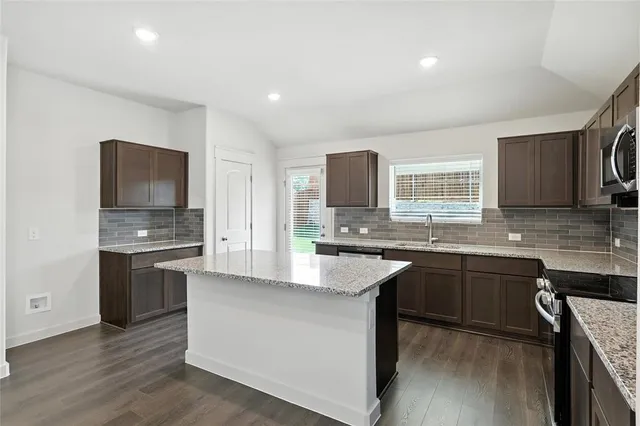a kitchen with stainless steel appliances granite countertop a sink dishwasher stove top oven and refrigerator