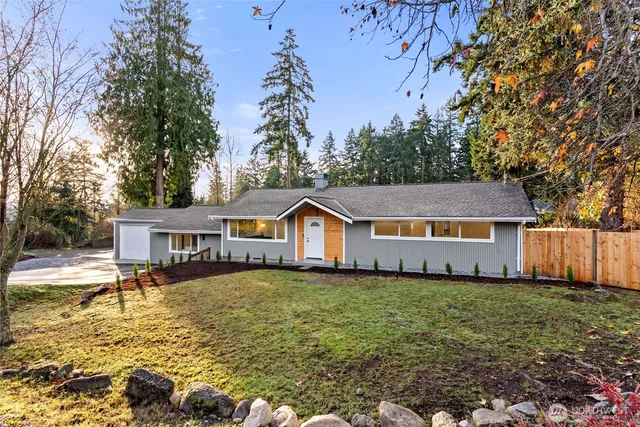 a view of a house with a big yard and large trees