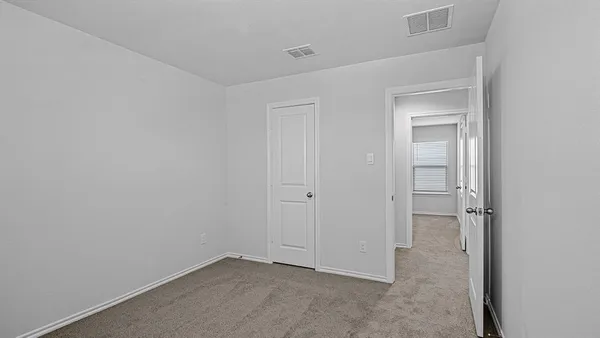 an empty room with closet and a hallway