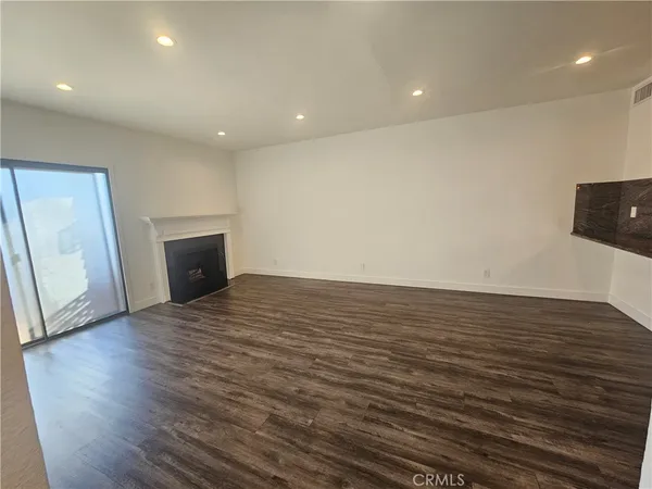 a view of empty room with wooden floor and fireplace