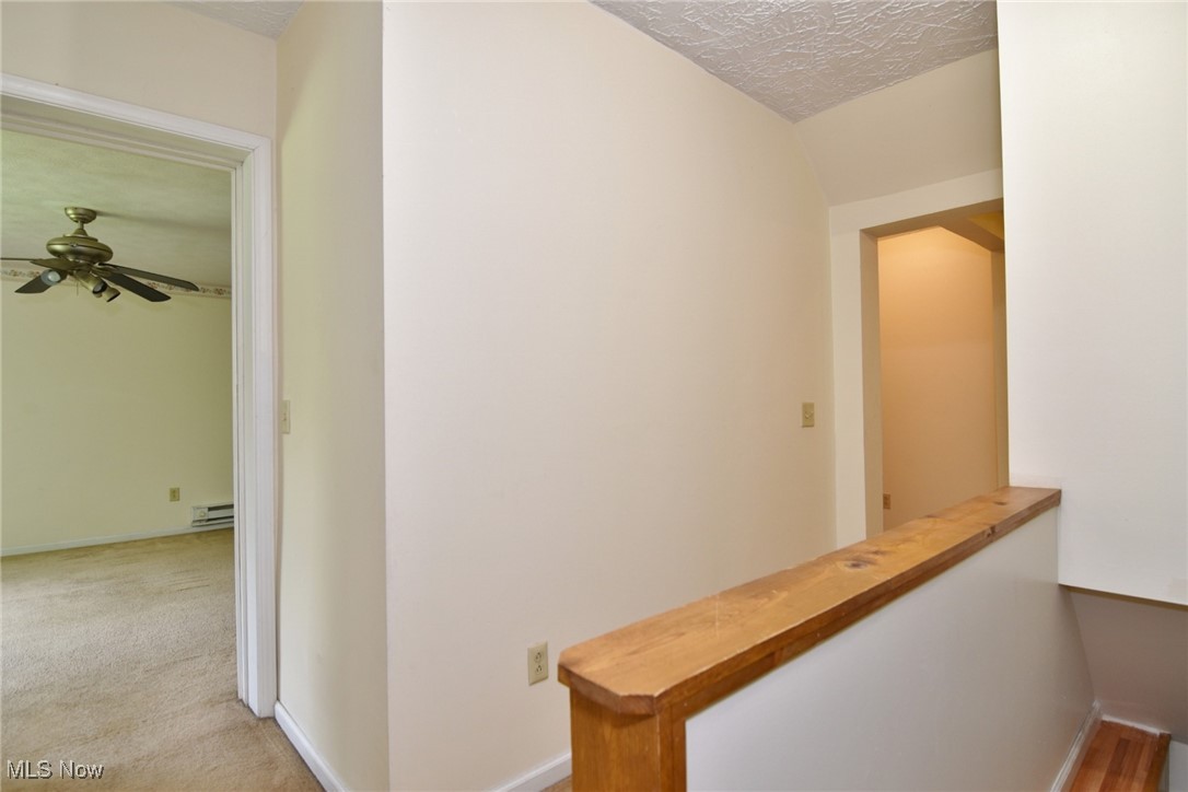 14405 Madison Road Middlefield, OH 44062 - Photo 20 of 30 Hall featuring baseboard heating, an upstairs landing, a textured ceiling, and light colored carpet
