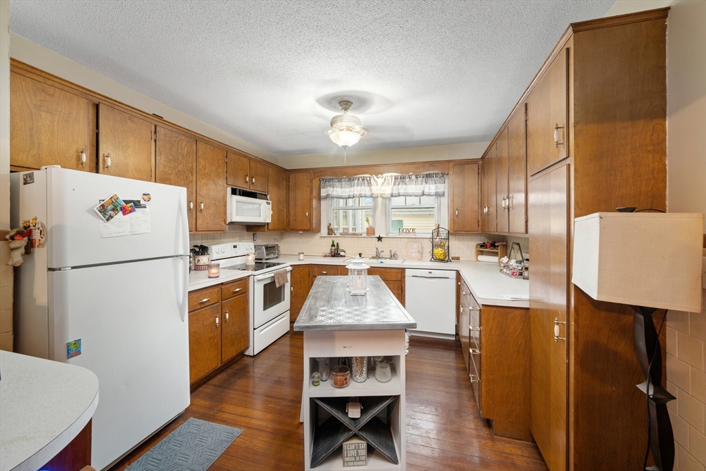 90 Meadow Road Woonsocket, RI 02895 - Photo 9 of 18 a kitchen with stainless steel appliances granite countertop a refrigerator a stove a sink dishwasher and a dining table with wooden floor