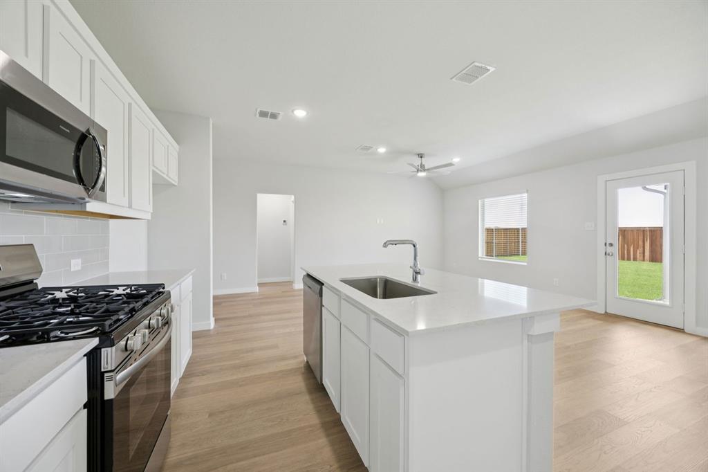 1153 Del Rio Drive Lavon, TX 75166 - Photo 6 of 27 a kitchen with stainless steel appliances a sink stove and cabinets