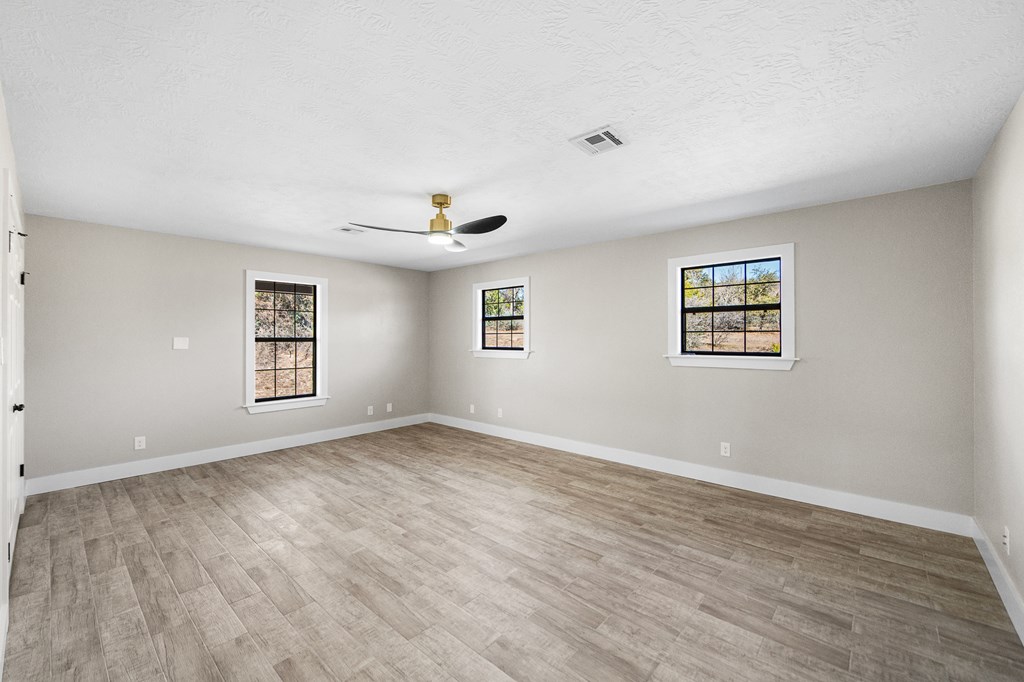 622 Paradise Ranch Road Fredericksburg, TX 78624 - Photo 40 of 90 a view of empty room with wooden floor and fan