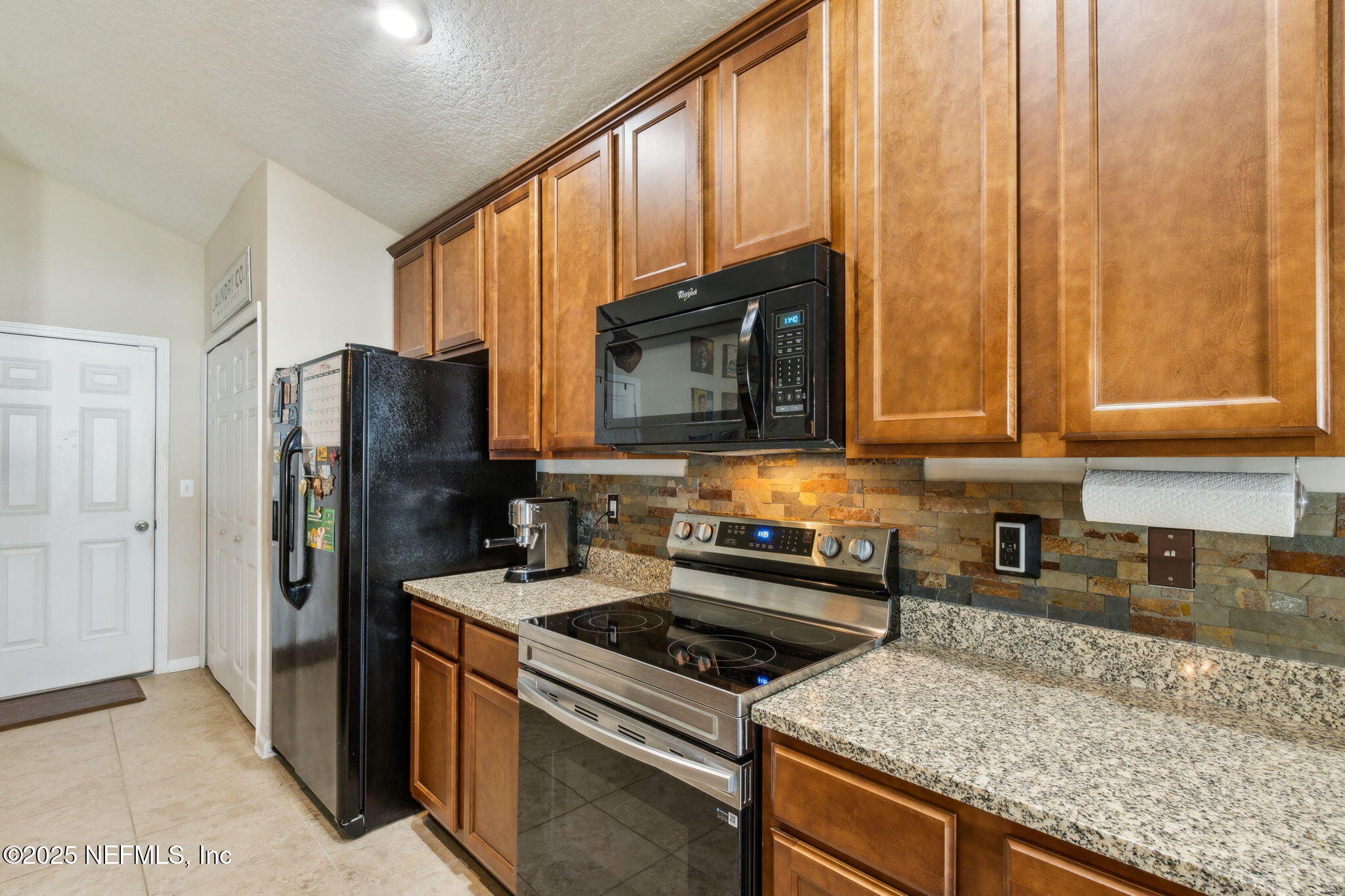 94055 Last Lane Yulee, FL 32097 - Photo 11 of 30 a kitchen with stainless steel appliances granite countertop a stove a refrigerator and a microwave