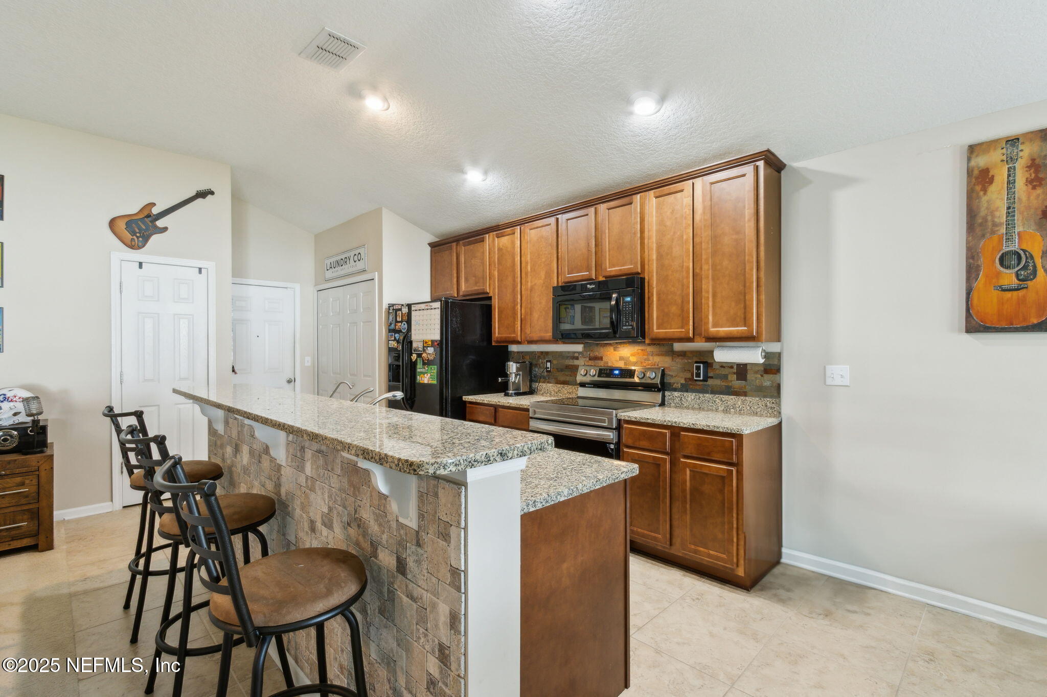 94055 Last Lane Yulee, FL 32097 - Photo 12 of 30 a kitchen with kitchen island granite countertop wooden cabinets and stainless steel appliances
