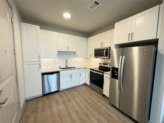 a kitchen with granite countertop a refrigerator stove top oven and sink