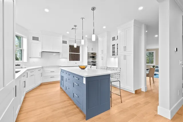 a large kitchen with a large counter top a sink stainless steel appliances and cabinets