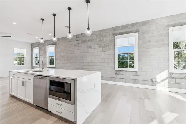 a large white kitchen with a large window a stove a sink and a refrigerator