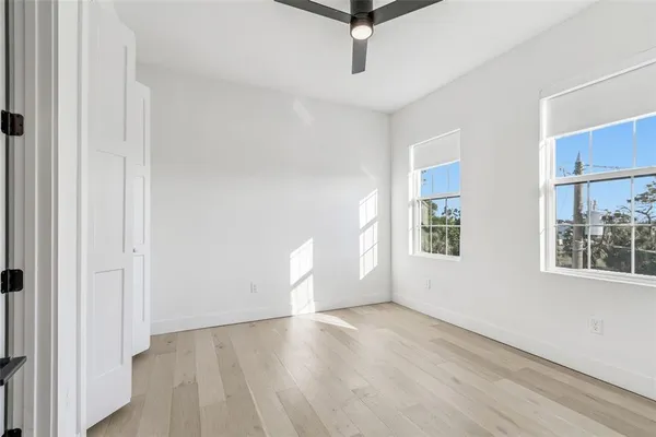 an empty room with wooden floor cabinet and windows