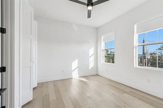 an empty room with wooden floor cabinet and windows